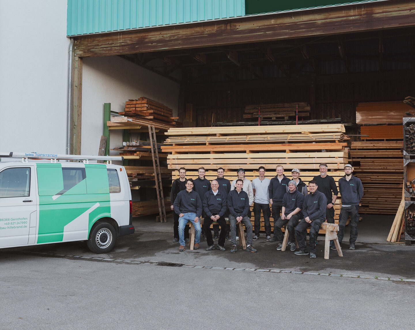 Das Team von Holzbau Hillebrand neben einem beschrifteten Transporter