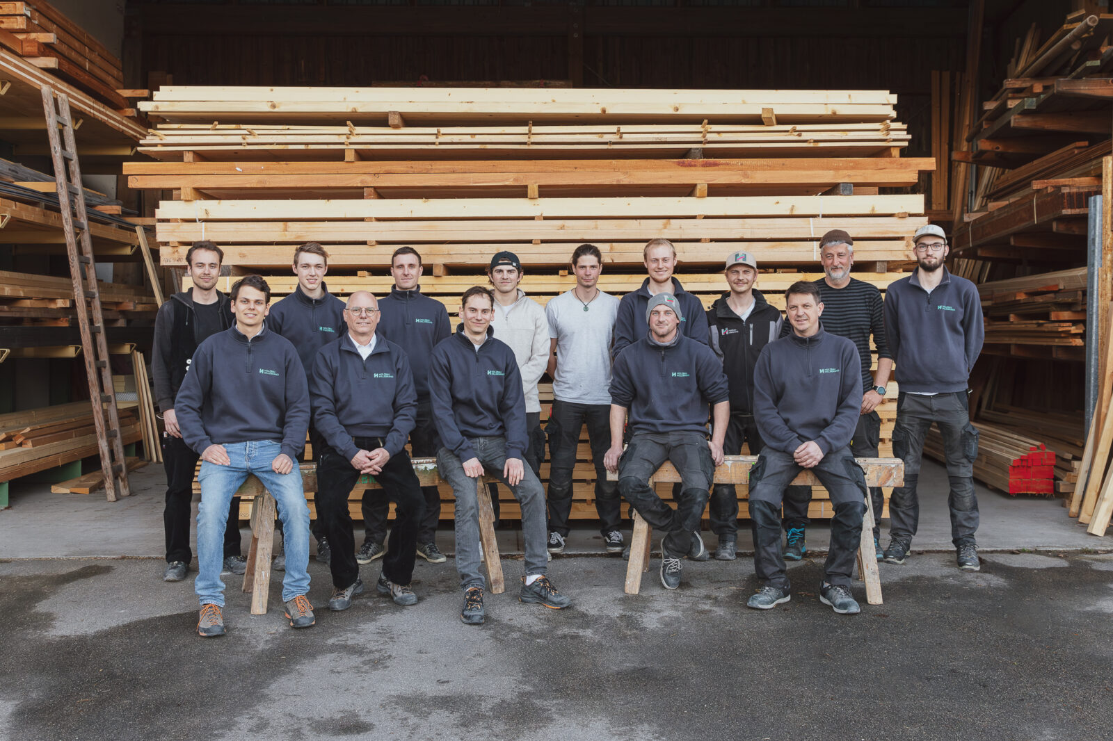 Das Team von Holzbau Hillebrand vor einem Stapel Holz